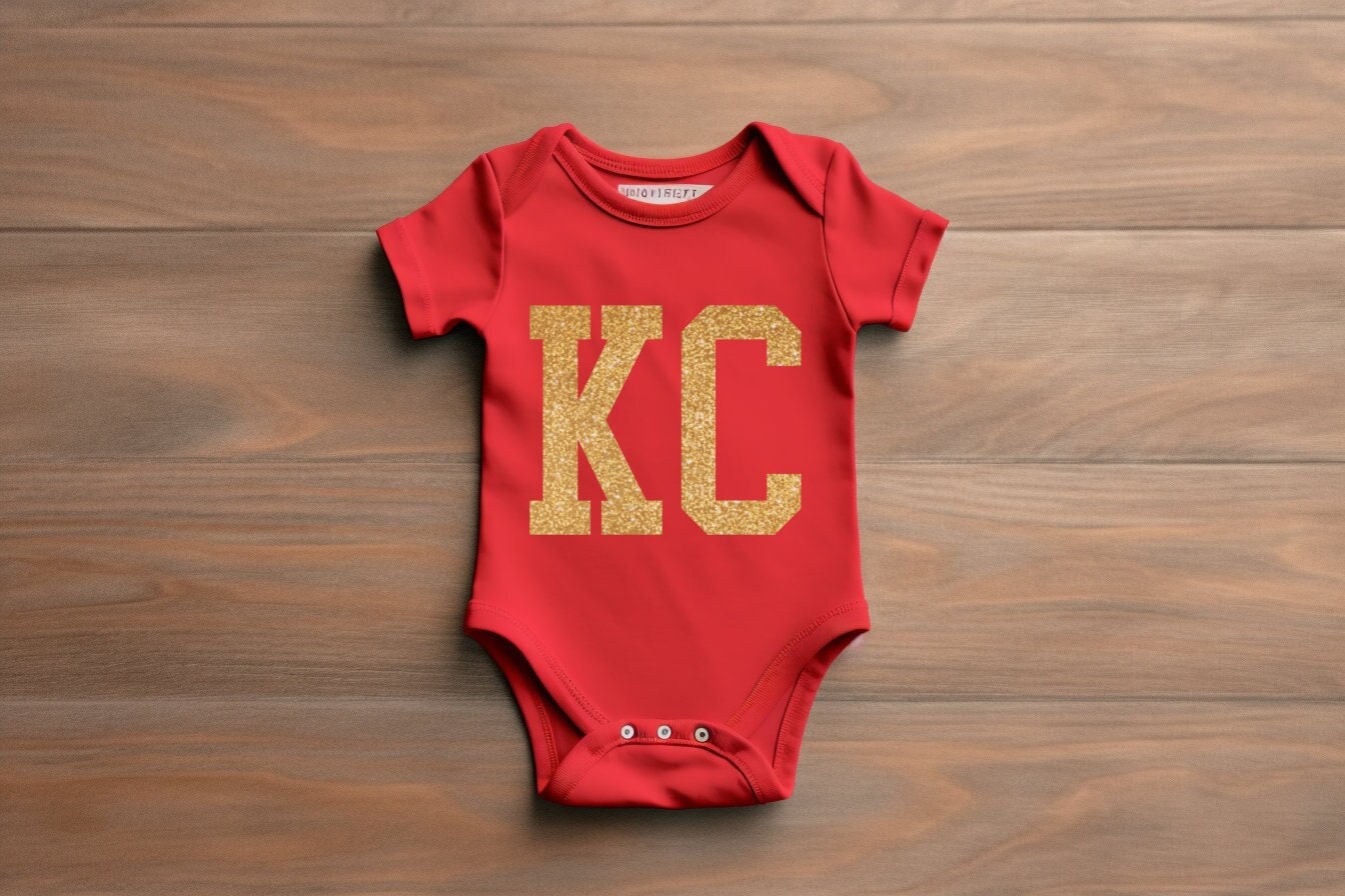 a baby onesie with the letter kc on it