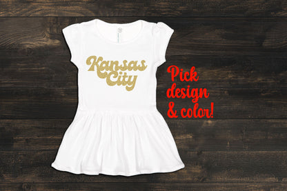 a white dress with gold lettering saying kansas city on it